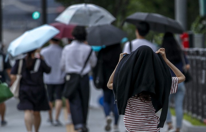 지난 17일 오후 서울 종로구 광화문광장 인근에서 갑자기 내리는 소나기에 시민들이 비를 피하고 있다.