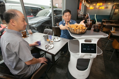 서울 송파구 BBQ 헬리오시티점에서 KT AI 서비스로봇이 치킨을 서빙하고 있는 모습