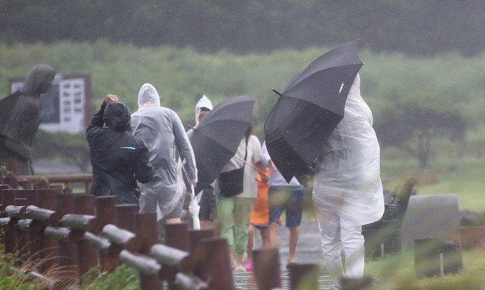 제11호 태풍 '힌남노' 간접영향으로 비바람이 부는 2일 오후 제주 서귀포시 대정읍 송악산에 우산을 쓴 관광객들이 걸어가고 있다. 기상청은 태풍 힌남노가 이날 우리나라를 향해 방향을 틀어 오는 6일 새벽께 서귀포 남동쪽 해상까지 접근할 것으로 예측했다.