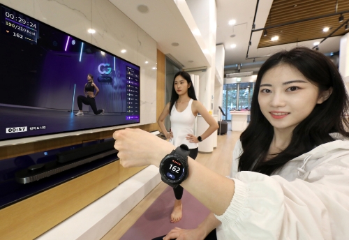 LG유플러스 모델이 U+tv와 갤럭시워치를 연동해 코코어짐 서비스를 이용하고 있는 모습.
