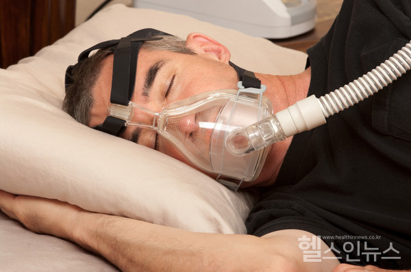수면무호흡증치료를위해양압기를착용하고자는남성.(사진.클립아트코리아)