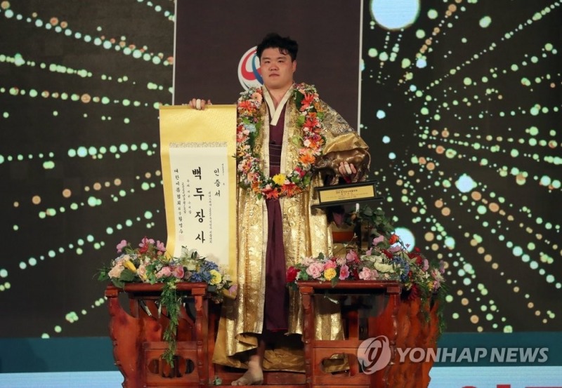 (경남 고성=연합뉴스) 12일 경남 고성군 고성국민체육센터에서 열린 위더스제약 2022 추석장사씨름대회 백두장사(140㎏ 이하)에 등극한 영암군 민속 씨름단 소속 장성우가 장사 인증서를 들고 꽃가마에 오르고 있다.