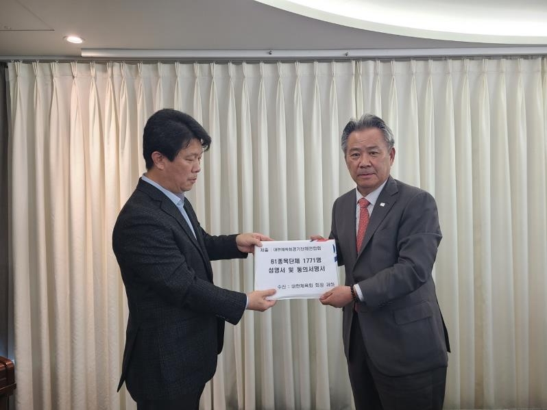 대한체육회경기단체연합회 김돈순 회장(왼쪽)이 이기흥 대한체육회장에서 대정부촉구성명서가 담긴 동의서를 전달하고 있다