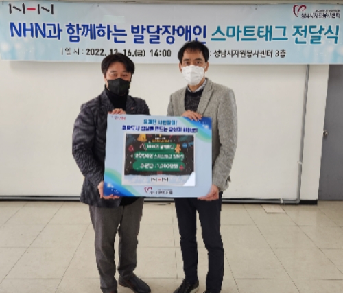 사진은 성남시 자원봉사센터 김재성 사무국장(사진 왼쪽)과 NHN 김재환 대외정책실장(사진 오른쪽)이 발달장애아동 사고 예방을 위한 스마트 태그 전달식을 마치고 기념촬영을 하고 있는 모습 / 사진 제공 = NHN