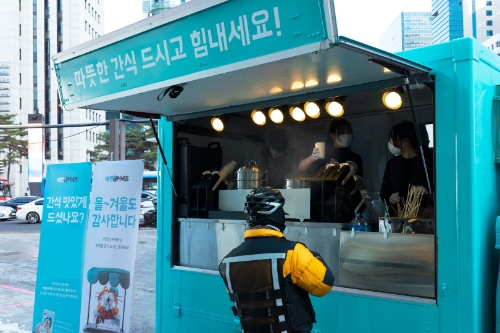 27일 강남역 9번 출구에서 진행된 우아한청년들 푸드트럭 나눔 행사에서 한 라이더가 따뜻한 음료와 음식을 제공받고 있다. / 사진 제공 = 우아한청년들