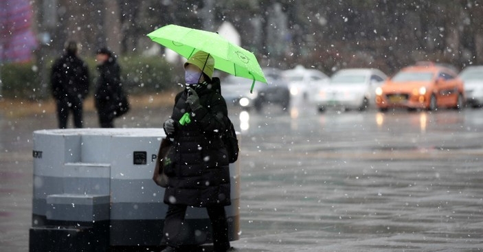 눈이 내린 지난 15일 서울 종로구 광화문광장에서 우산을 쓴 시민들이 길을 걷고 있다.