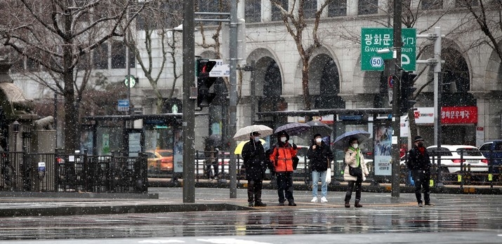 눈이 내린 지난 15일 서울 종로구 광화문광장에서 우산을 쓴 시민들이 길을 걷고 있다.