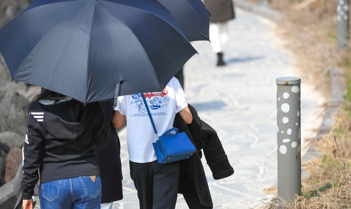 추위가 풀려 포근한 날씨를 보이는 지난 5일 오후 제주시 애월읍 한담해안산책로에서 우산을 쓴 관광객들이 가벼운 옷차림으로 걸어가고 있다.