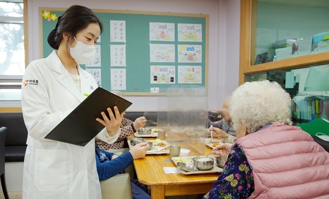 아워홈 영양사가 서울 마포구 한서데이케어센터에서 ‘인지기능개선 관리 식단’을 시설 이용 노인에게 소개하고 있다. [사진=아워홈]