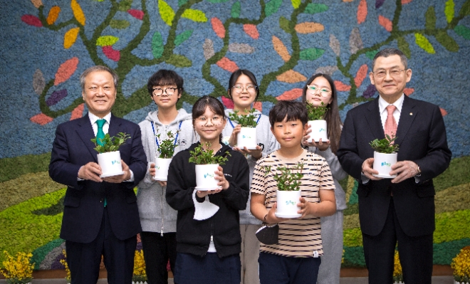 한화그룹은 ‘맑은학교 만들기’ 2차년도 대상 학교에 설비 지원을 완료하고 지난 21일 청주 수성초등학교에서 기념식을 진행했다고 22일 밝혔다. 사진은 한화사회봉사단 김신연 사장(오른쪽)과 환경재단 최열 이사장(왼쪽)이 수성초 학생들과 함께 벽면에 조성된 모스월 앞에서 공기정화 식물을 들고 있는 모습. (사진 = 한화그룹 제공)