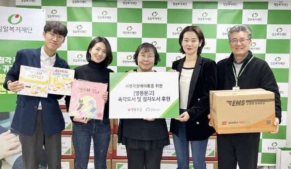 밀알복지재단 헬렌켈러센터 관계자와 시청각장애아동 어머니(오른쪽에서 두 번째)가 5일 촉각도서와 점자도서를 전달받고 있다.