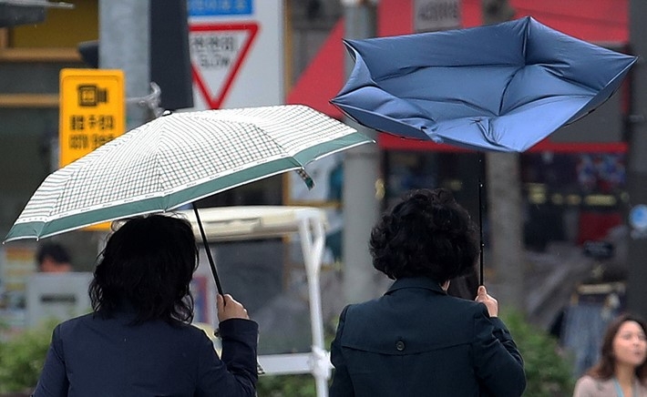 서울 지역에 강풍주의보가 내려진 지난 11일 오후 서울 동작구 거리에서 한 시민이 쓴 우산이 뒤집히고 있다.