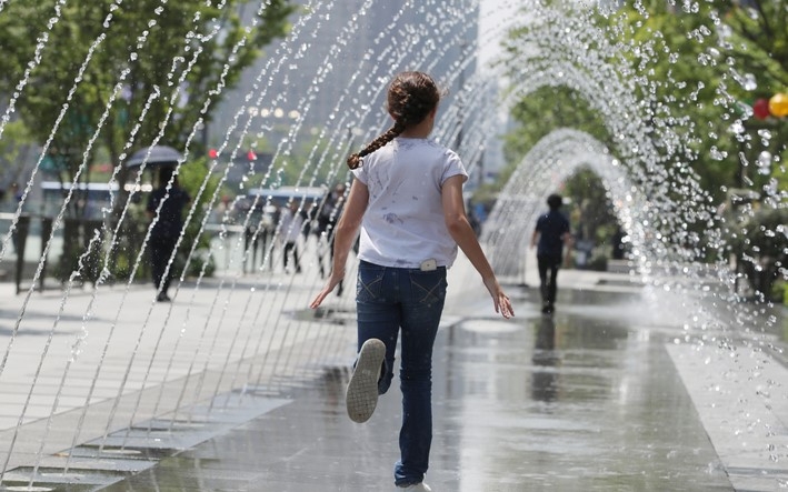 맑은 초여름 날씨를 보인 9일 서울 광화문광장 분수대에서 외국인 관광객이 즐거운 시간을 보내고 있다.