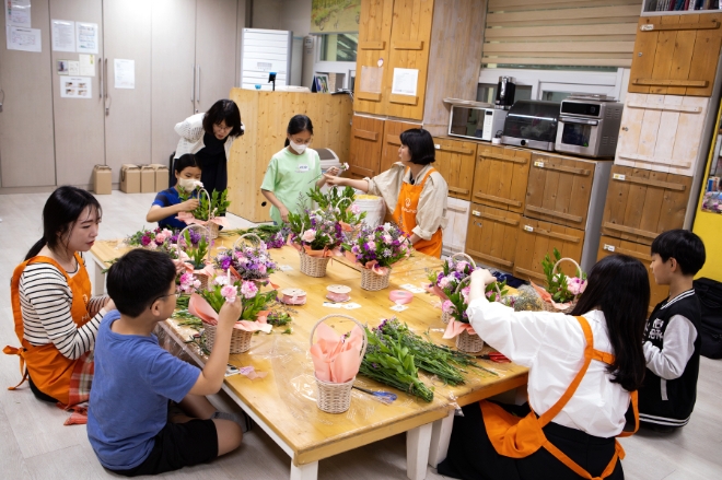 한화생명 임직원으로 구성된 캘리그라피 및 플로리스트 전문 봉사자들이 민들레학교지역아동센터 아동들과 카네이션 꽃 바구니와 응원 메시지가 담긴 선물을 만들고 있다. / 사진 = 한화생명 제공