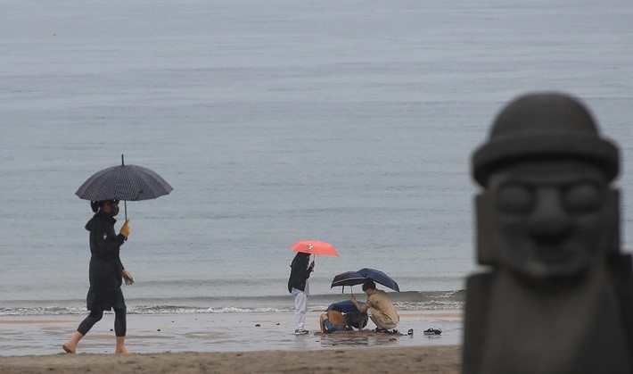 비가 내리기 시작한 지난 3일 오후 제주시 이호해변에 우산을 쓴 관광객들이 지나가고 있다.