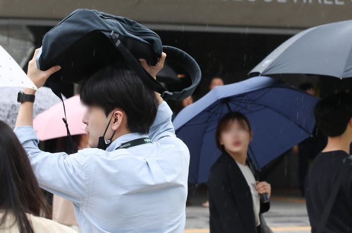 지난 8일 오후 서울 중구 서울시청 인근에서 한 시민이 가방을 이용해 비를 피하고 있다. 