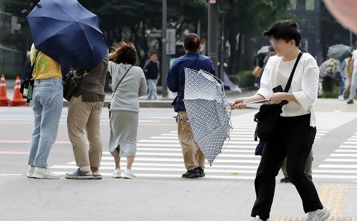  소나기가 내리고 있는 지난 10일 서울 광화문 네거리에서 한 시민이 강풍에 우산을 붙잡고 있다.