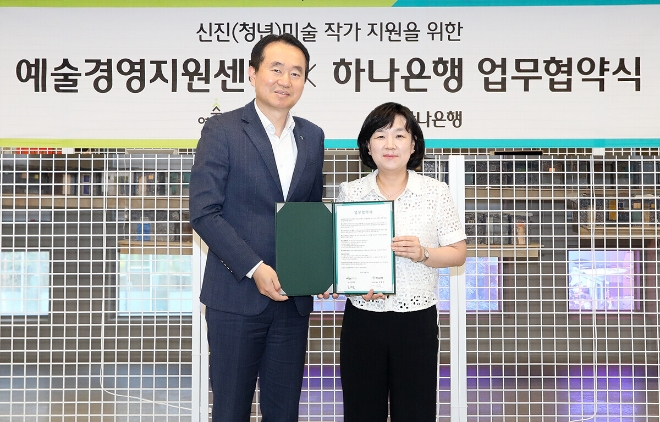 하나은행은 지난 16일 서울시 을지로4가에 위치한 하나은행의 개방형 수장고 ‘H.art1(하트원)’에서 예술경영지원센터와신진(청년) 미술 작가 발굴 및 작품 판로 지원을 위한 전략적 업무협약(MOU)을 체결했다.업무협약식에 참석한 김영훈 하나은행 자산관리그룹장(왼쪽)이 김승연 예술경영지원센터 본부장과 함께 기념 촬영을 하고 있다. / 사진 = 하나은행 제공