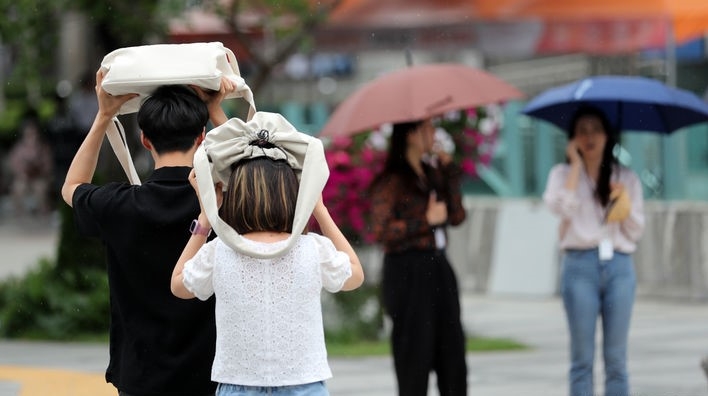 지난 20일 오후 서울 광화문 사거리에서 시민들이 가방으로 머리를 가린 채 횡단보도를 건너고 있는 모습.
