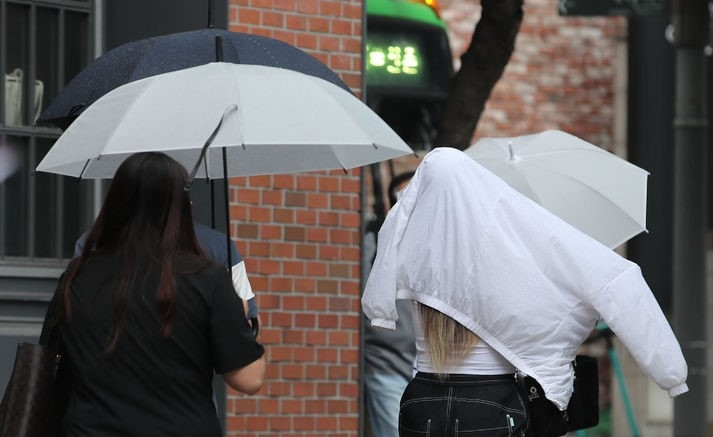 비가 내리는 지난 14일 오후 서울 서대문구 신촌역 인근에서 시민이 겉옷으로 비를 피하고 있다.