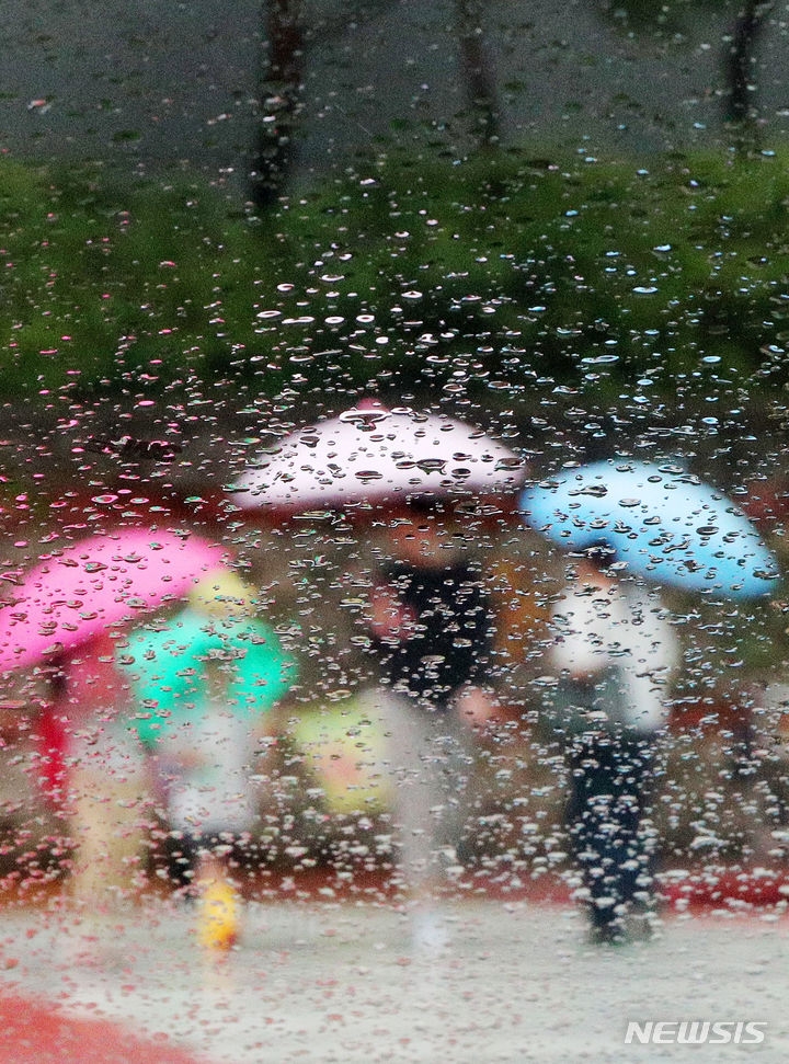 26일 부산 남구의 한 횡단보도에서 시민들이 우산을 쓴 채 발걸음을 재촉하고 있는 모습.