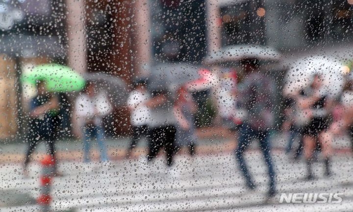 장맛비가 내리는 26일 부산 남구의 한 횡단보도에서 시민들이 우산을 쓴 채 발걸음을 재촉하고 있다.