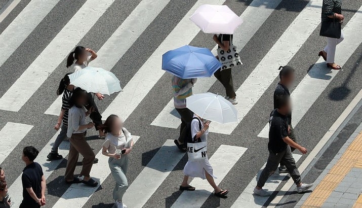 무더운 날씨를 보인 19일 부산 연제구의 한 도로에서 양산을 쓴 시민들이 횡단보도를 건너고 있는 모습.