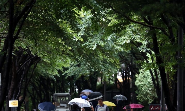 장마전선이 북상하면서 서울 등 수도권에 비가 내리는 지난달 26일 오전 서울 마포구 경의선숲길에서 시민들이 우산을 쓰고 출근길 발걸음을 재촉하는 모습.