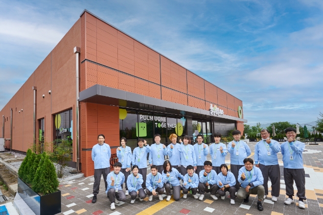 풀무원 투게더 공장에서 일하는 장애인 근로자들이 공장 앞에서 파이팅을 외치며 기념 촬영을 하고 있다. / 사진=풀무원 제공