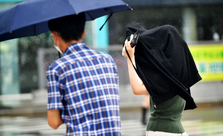 광주·전남에 장맛비가 내리는 4일 오전 광주 동구 구시청 주변에서 시민들이 우산과 외투로 비를 피하며 횡단보도를 지나고 있다.