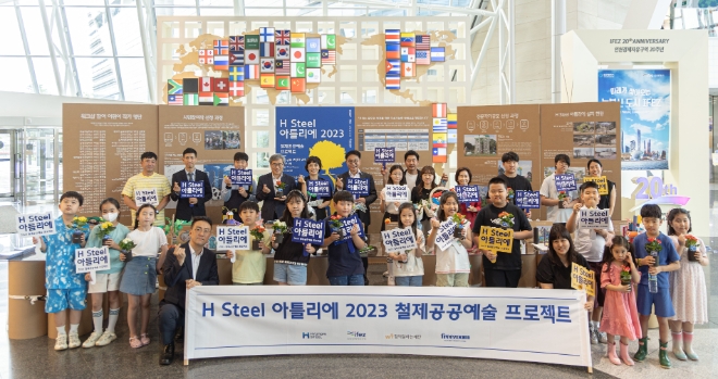 안동일 현대제철 사장(후열 좌측 여섯번째)과 이행숙 인천시 정무부시장(후열 좌측 열번째), 김진용 인천경제자유구역 청장(후열 좌측 네번째), 공모 당선 작가, 지역 아동들이 H-아틀리에 포토월에서 기념 촬영을 하고 있다. / 사진=현대제철 제공