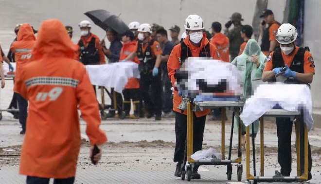 전날 내린 비로 인해 차량 15대가 물에 잠기고 최소 11명이 실종된 충북 청주시 흥덕구 오송읍 궁평2지하차도에서 소방당국이 시신을 구급차로 이동시키고 있다.(사진=뉴시스)