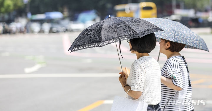 더운 날씨를 보인 지난 20일 서울 중구 세종대로에서 시민들이 양산으로 햇빛을 가린 채 이동하고 있다. 