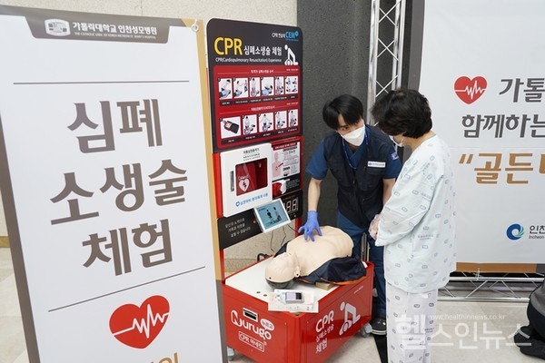 심폐소생술체험부스에서직원이체험을돕고있다.