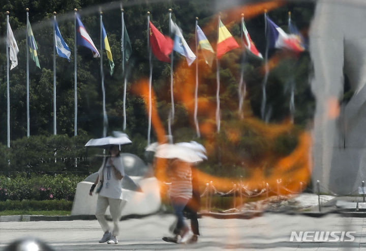 지난 3일 서울 송파구 올림픽공원 평화의문에 설치된 성화 뒤 도심풍경이 아른거리고 있는 모습.