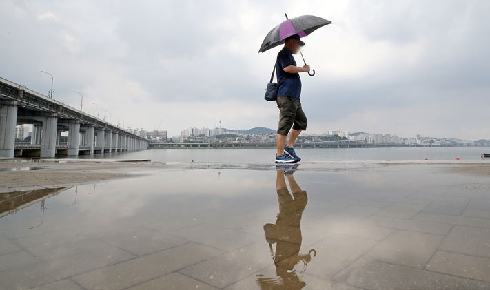 소나기가 내린 지난 6일 오후 서울 서초구 반포 한강공원에서 시민이 우산을 쓰고 이동하고 있다.