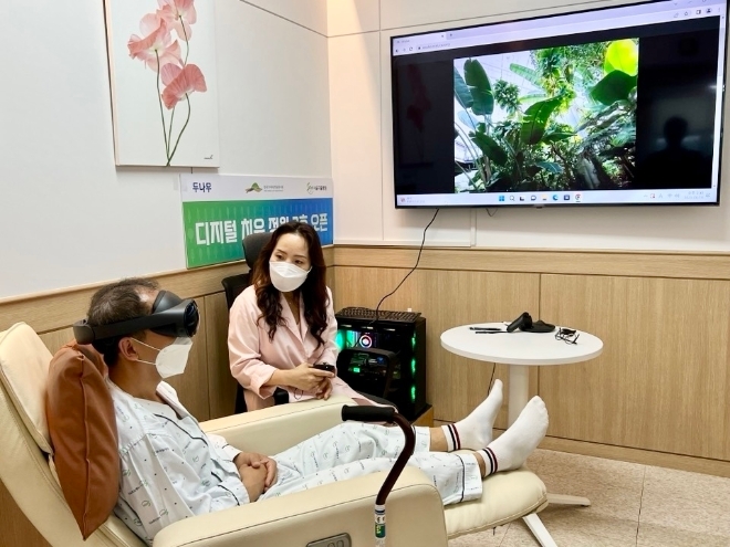디지털 치유 정원 2호점이 설치된 '서울재활병원'에 입원 중인 환자가 국립세종수목원을 촬영한 가상현실(VR) 영상을 직접 체험하고 있다. / 사진=두나무 제공