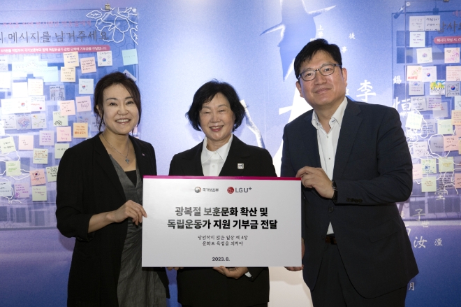 일상비일상의틈byU+에서 열린 기부금전달 약정식에서 (왼쪽부터)정혜윤 LG유플러스 마케팅그룹장, 문영숙 (사)독립운동가 최재영 기념사업회 이사장, 오진영 국가보훈부 보훈정책실장이 기념촬영을 하고 고객 참여 메시지를 살펴보고 있는 모습. / 사진=LG유플러스 제공