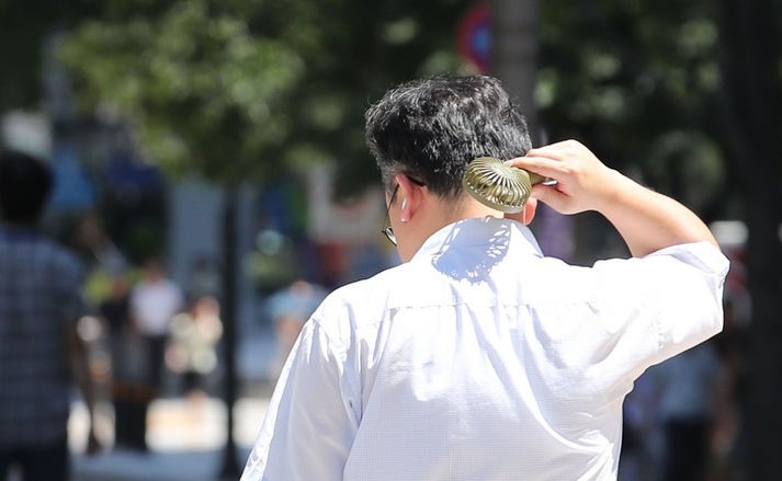서울지역에 폭염 경보가 발령된 지난 8일 오후 서울 종로구 광화문광장에서 한 시민이 선풍기를 목에 쐬는 모습.