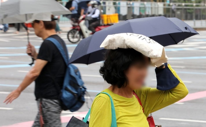 비가 내린 지난 22일 오전 서울 종로구 세종대로 인근에서 한 시민이 가방으로 비를 피하고 있다.