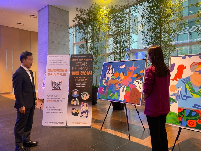 최현만 미래에셋증권 회장(왼쪽)이 28일 서울 중구 미래에셋센터원빌딩 2층 로비에서 개최된 발달장애 예술가 작품 전시회에서 신동민 작가의 와뛰디 작품을 감상하고 있다. / 사진=미래에셋증권 제공
