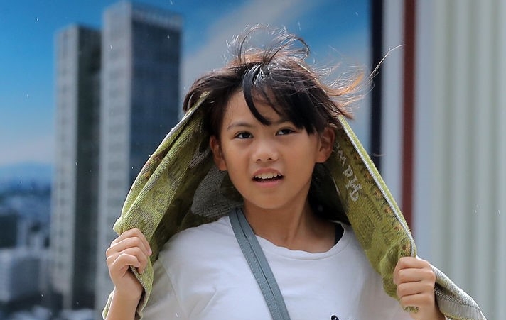 소나기가 내렸다 그치기를 반복한 지난달 22일 오후 명동역 인근에서 한 아이가 수건을 뒤집어 쓰고 서둘러 이동하고 있다.