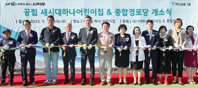 하나금융그룹은 지난 7일 오후 경기도 의정부시와 함께 지역 내 민관 협력으로 건립한 ‘국공립 새시대 하나어린이집’의 개원식을 가졌다고 8일 밝혔다. 사진은 이날 개원식에 참석한 김동근 의정부시장(사진 왼쪽에서 여섯번째)과 김귀호 하나은행 의정부금융센터 지점장(사진 왼쪽에서 다섯번째)이 참석 내·외빈과 함께 축하 테이프 커팅을 하고 있는 모습. (사진 = 하나금융그룹 제공)