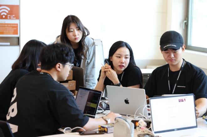 SK텔레콤(SKT)은 하나금융그룹과 함께 대학생 대상 1박 2일 일정의 AI기술 기반 ‘TECH4GOOD 해커톤’을 성공적으로 마쳤다고 14일 밝혔다. 사진은 해커톤 현장에서 대학생들이 멘토와 함께 아이디어 회의를 하는 모습. (사진 = SKT 제공)