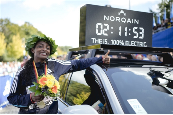 티지스트 아세파(에티오피아)가 2023 베를린 마라톤에서 여자 마라톤 세계 신기록을 수립한 뒤 영광의 월계관을 쓰고 기뻐하며 시계를 배경으로 기념 포즈를 취하고 있다. [사진=AP PHOTO]