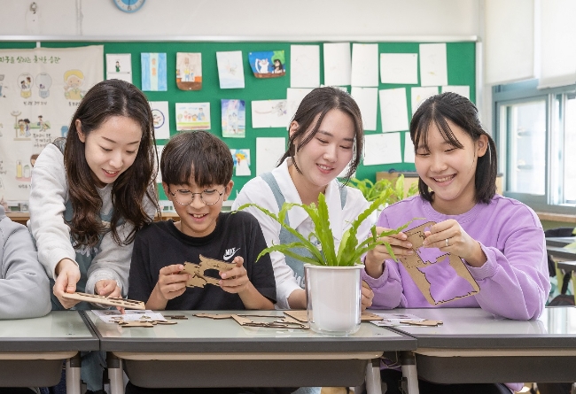 코웨이 임직원 봉사자들과 초등학생들이 간이 공기청정기를 제작하고 있다.