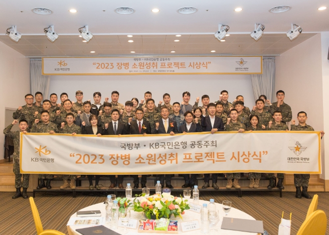 29일 서울시 용산구에 위치한 국방컨벤션에서 열린 ‘2023 장병소원성취 프로젝트’ 시상식에서 윤봉희 국방부 정책기획관(맨 앞 줄 좌측 6번째), 김동록 KB국민은행 기관고객그룹 대표(맨 앞 줄 좌측 7번째) 및 관계자들이 수상 장병들과 기념사진을 촬영하고 있다. / 사진=KB국민은행 제공