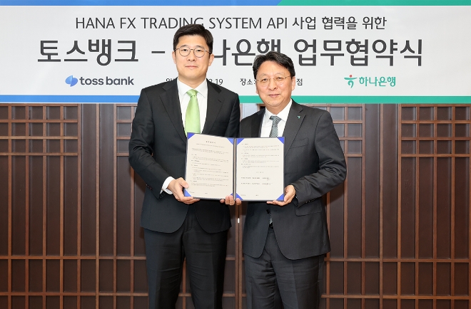 하나은행은 19일 오전 을지로 본점에서 토스뱅크와 실시간 환율을 적용한 『24시간 다통화 FX 거래』 활성화를 위한 업무협약을 체결했다. 협약식에 참석한 남궁원 하나은행 자금시장그룹 부행장(사진 오른쪽)과 김지웅 토스뱅크 최고전략책임자(사진 왼쪽)가 협약서를 들고 기념촬영을 하고 있다. / 사진=하나은행 제공