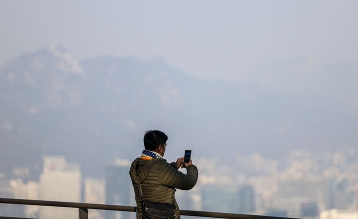 초미세먼지가 '나쁨' 수준을 보인 전날(26일) 서울 남산을 찾은 여행객이 도심 배경으로 사진을 찍고 있다.