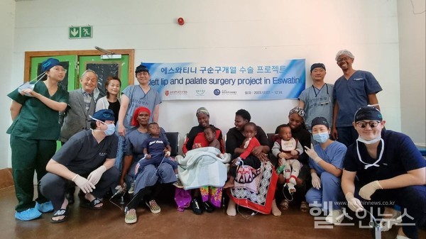 봉사팀이수술한환아들및보호자들과기념사진을찍고있다(현수막좌측이태열교수,우측김덕우교수)